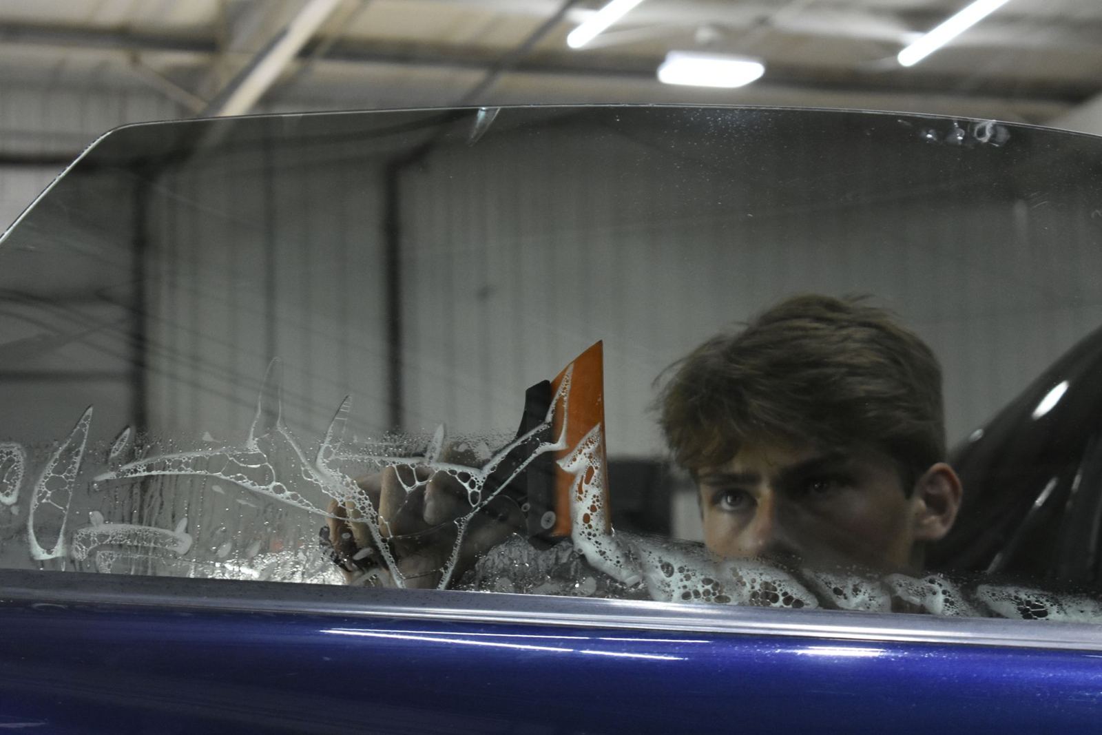 Window tint film being squeegeed onto a car window